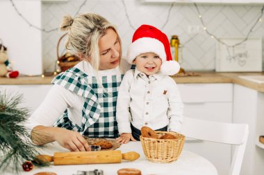 Bir anne ve küçük oğlu Noel kurabiyeleri hazırlıyorlar. Mutfakta mutlu bir aile. Tatil hazırlıkları, Noel havası, aile gelenekleri.