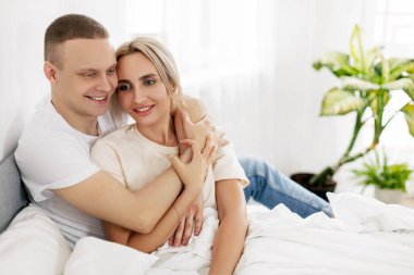 Bir erkek ve bir kız kucaklaşır ve evdeki kanepede oturup birlikte vakit geçirmekten zevk alırlar.