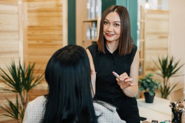 Makyaj sanatçısı kuaförde bir kız için makyaj yapar, ruj sürer, resmi tamamlar. Güzellik ve özgüven kavramı