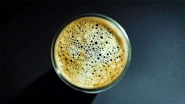 Káva kapka do plněné sklenice ve zpomaleném filmu. — Stock video