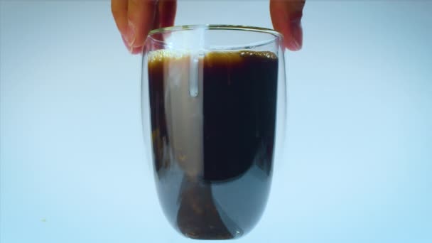 Le mani di stilista di cibo girano un bicchiere di caffè dopo aver versato il latte su vetro. Al rallentatore. Studio ripresa pubblicità. — Video Stock