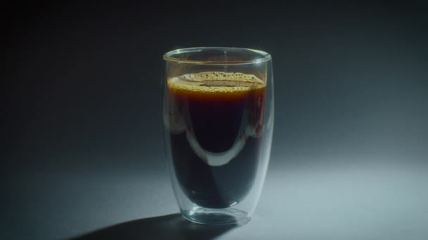 Il vetro di caffè con schiuma sta su sfondo nero. Girare bevanda annuncio commerciale in studio. — Video Stock