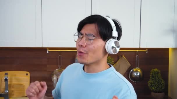 Radostný Asijský Vietnamka Chlap Bezdrátových Sluchátkách Doma Kuchyně Baví Poslech — Stock video