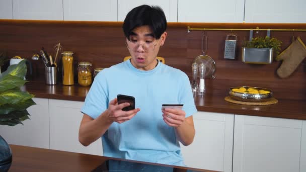 Joven Hombre Asiático Sentado Cocina Moderna Implicado Uso Teléfono Inteligente — Vídeos de Stock