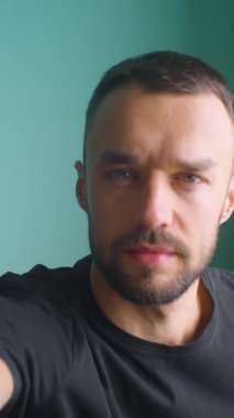 Dikey adam kamerayı video blogu için hazırlıyor. Prefransları kontrol etmek, düşünmek, saçlara dokunmak, kameraya bakmak. Çevrimiçi öğretmen koçu web cam çağrı konferansına hazır olun..