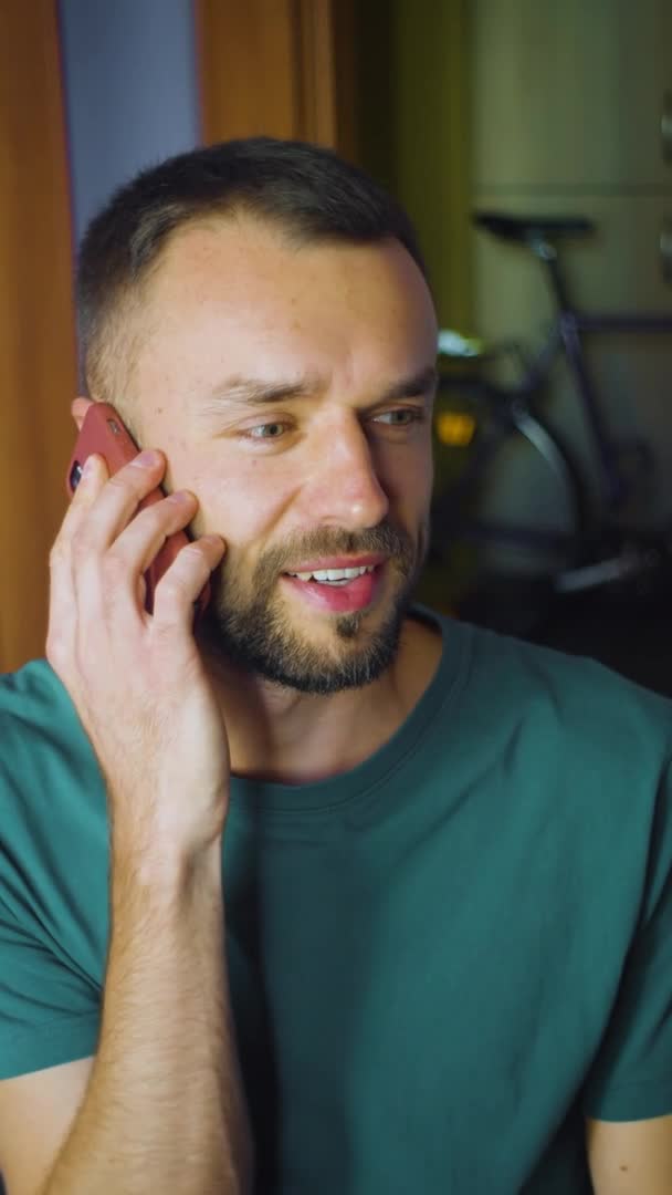 Homme américain vertical reçoit un appel téléphonique, parler et sourire, assis à la maison salon. caucasien mâle bénéficie de technologies sans fil — Video