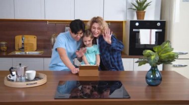 Utangaç çocuklu melez bir aile tablet kullanarak video araması yapıyor. Kafkas ve Güney Asyalı ebeveynler internet bağlantısı üzerinden akrabalarıyla konferans görüşmesi için cihaz kullanıyorlar. Çevrimiçi insanları selamla.