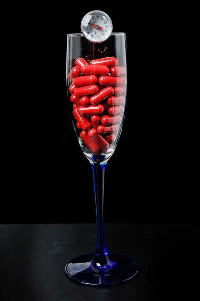 Красная капсула в стеклянной тарелке — стоковое фото