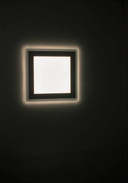 Square lamp glows on the ceiling in the dark. Space for inscription. Quality image for your project