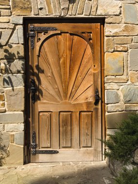 Tahta kapılar, taş duvarlar, bitki gölgeleri, el yapımı işler.