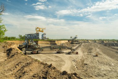 Endüstriyel maden ocağı manzarası. Makineler çalışıyor. Bölgede bakır, gümüş, altın ve kahverengi kömür madeni çıkarıldı. Açık bir çukur kahverengi kömür madeninde kazıcı..