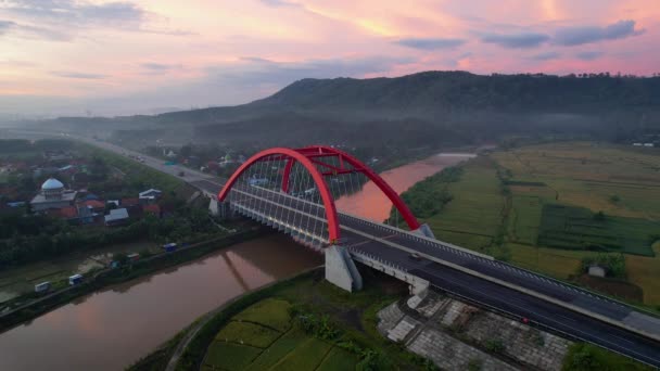 トランスジャワ有料道路 バタンの象徴的な赤い橋であるKalikuto橋の空中写真日の出 2021年11月11日インドネシア中部ジャワ — ストック動画