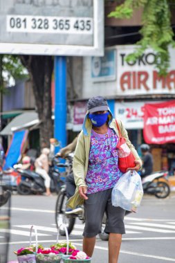 Yağmurdan sonraki bulutlu bir sabahta asfalt yolda arabasını çeken çalışkan bir çöpçü. Solo - Endonezya. 9 Aralık 2021