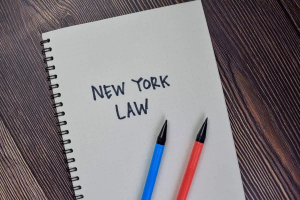 木製のテーブルに隔離された本にニューヨークの法律の書き込み — ストック写真