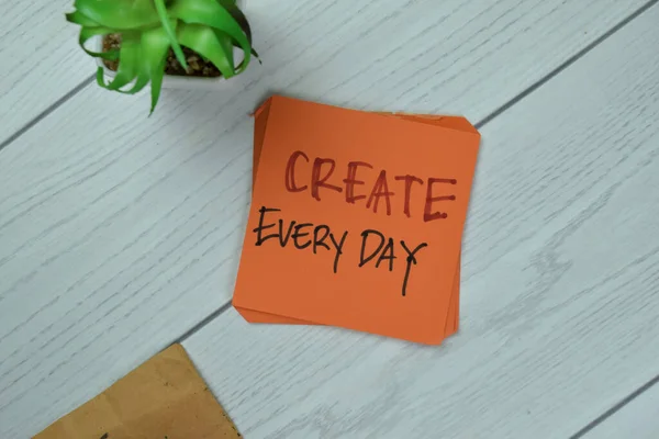 Concept of Create Every day write on sticky notes isolated on Wooden Table.