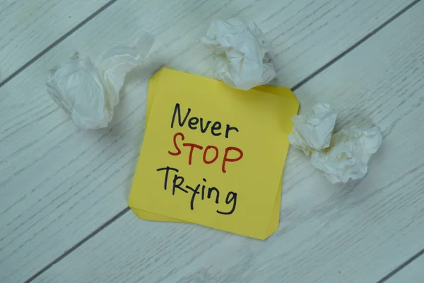 Concept of Never Stop Trying write on sticky notes isolated on Wooden Table.