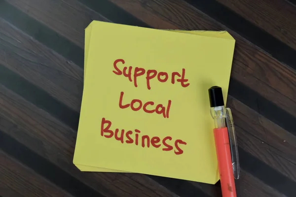 Concept of Support Local Business write on sticky notes isolated on Wooden Table.