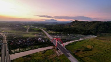 Aerial view of the Kalikuto Bridge, an Iconic Red Bridge at Trans Java Toll Road, Batang when sunrise. Central Java, Indonesia, August 24, 2022