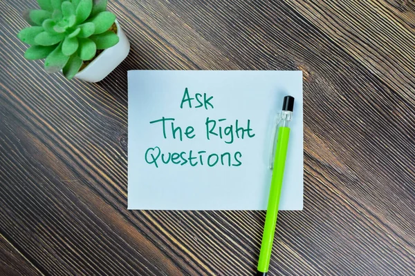 Concept of Ask The Right Questions write on sticky notes isolated on Wooden Table.