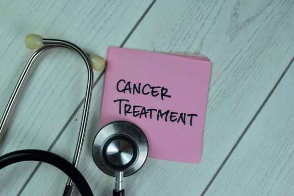 Concept of Cancer Treatment write on sticky notes isolated on Wooden Table.