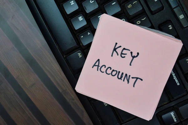 Concept of Key Account write on sticky notes with keyboard computer isolated on Wooden Table.