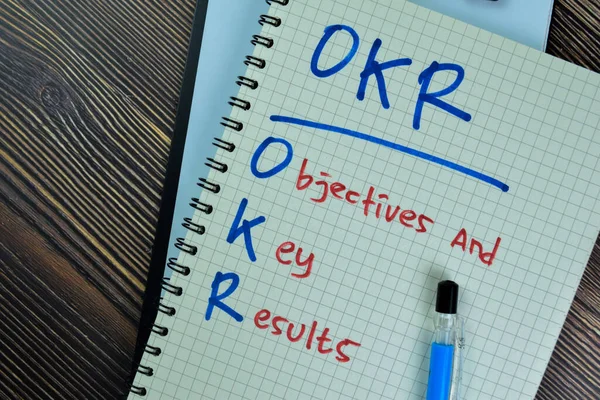 Concept of OKR - Objectives and Key Results write on a book isolated on Wooden Table.