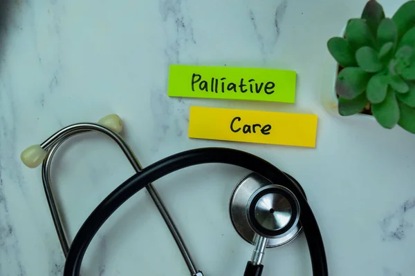 Concept of Palliative Care write on sticky notes with stesthoscope isolated on Wooden Table.