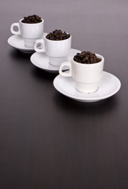 kahverengi masa üstünde kahve çekirdekleri ile 3 beyaz bardak