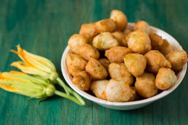 Yeşil zemin üzerinde kabak çiçekli çörekler. Napoli mutfağının tipik bir lezzeti içinde kabak çiçekleri olan kızarmış köftelerdir, kabak çiçekleri pişirmek için harika bir yoldur..