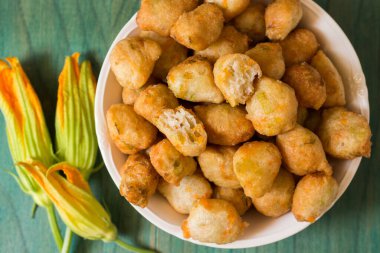 Yeşil zemin üzerinde kabak çiçekli çörekler. Napoli mutfağının tipik bir lezzeti içinde kabak çiçekleri olan kızarmış köftelerdir, kabak çiçekleri pişirmek için harika bir yoldur..