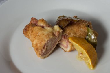 Tütsülenmiş scamorza peynirli tavuk dürümleri ve pişirilmiş jambon ve ekmek kırıntıları. Saha yaprağı ve limon dilimleriyle pişirilmiş.