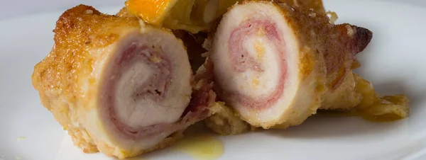 Tütsülenmiş scamorza peynirli tavuk dürümleri ve pişirilmiş jambon ve ekmek kırıntıları. Saha yaprağı ve limon dilimleriyle pişirilmiş.