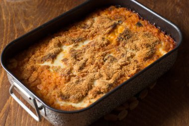 Ahşap zemin üzerinde pişirme kabında vejetaryen pilavı.