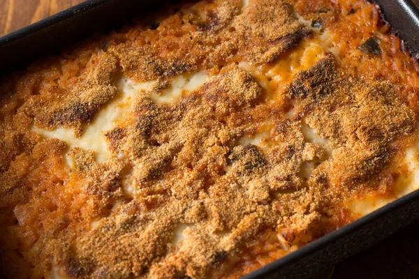 Ahşap zemin üzerinde pişirme kabında vejetaryen pilavı.