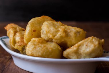 Kızarmış morina, ahşap arka planda servis edilen tabakta servis edilir.