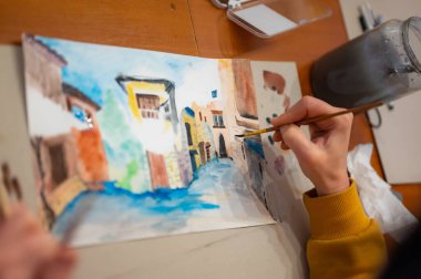 Canlı suluboya resim sürecinin kapanışı. Tablonun üzerinde el fırçası. Kağıt tahtada renkli ortaçağ şehir caddesi.