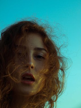 Şafak vakti plajda kıvırcık saçlı, rahat genç bir bayana yaklaş..