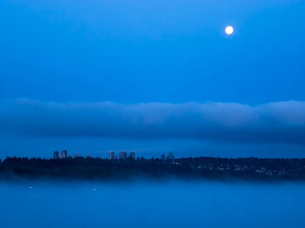 Paisaje urbano en la noche con luna llena en el cielo — Foto de Stock