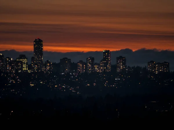 Stadtbeleuchtung nach Sonnenuntergang vor dunklerem Himmel — Stockfoto
