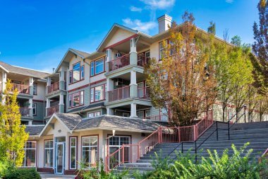 Low-rise residential building on blue sky background with stairs on the side through the land terrace