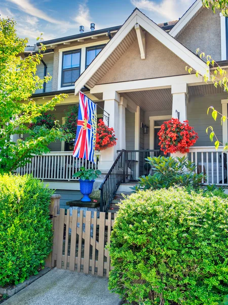 Porch of residential house with British Columbia flag above the entrance.