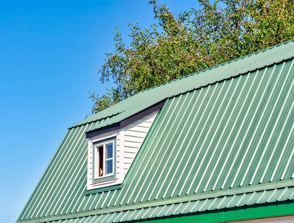 The window on green roof of a farm barn.