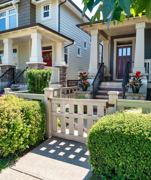 A perfect neighborhood. Porch and entrance door of a nice residential house with two flower pots in front.