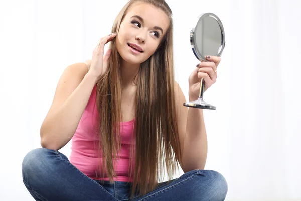 Girl sitting on the bed and holding a mirror — Stock Photo, Image