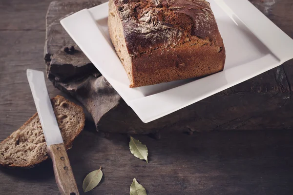 Нож с коричневым хлебом на тарелке — стоковое фото