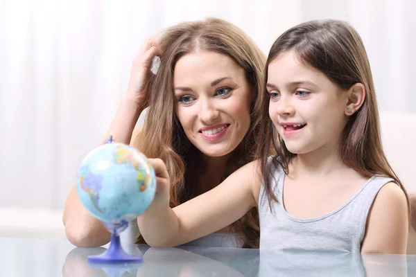 Mãe e filha olhando para um globo — Fotografia de Stock