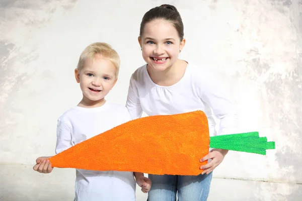 Irmão e irmã posando com cenoura pintada — Fotografia de Stock