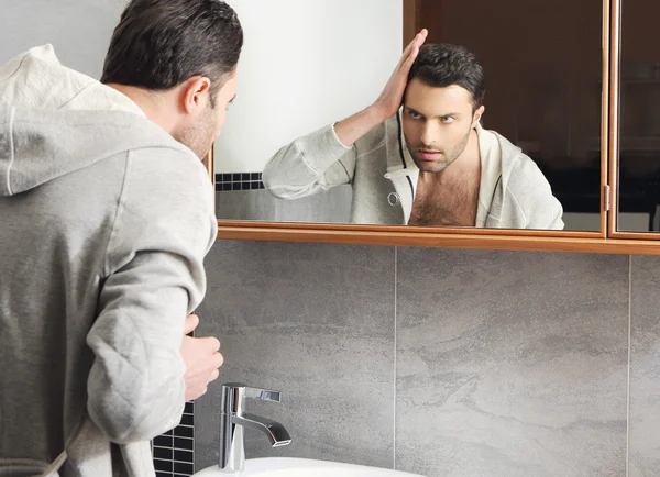 Young man looks at himself in the mirror — Stock Photo, Image