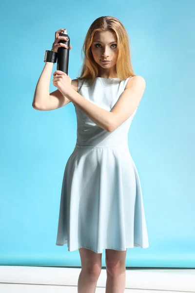 Bella ragazza in un vestito bianco che tiene una bottiglia con lacca per capelli — Foto Stock