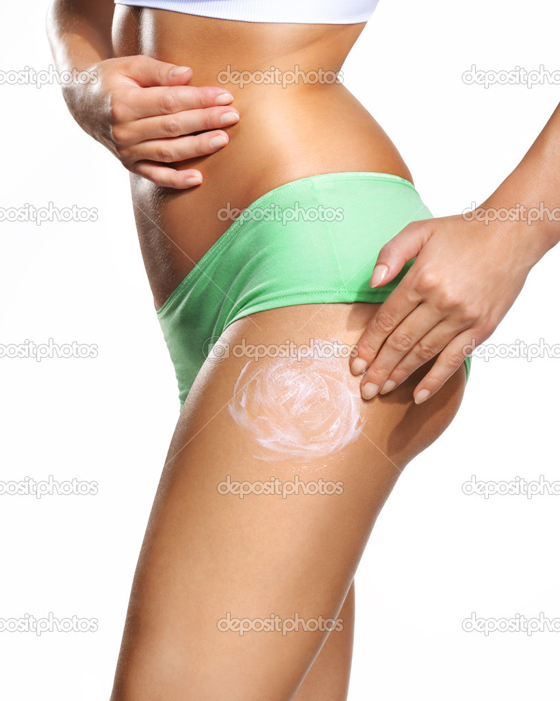 Young beautiful woman applying body lotion on her attractive legs